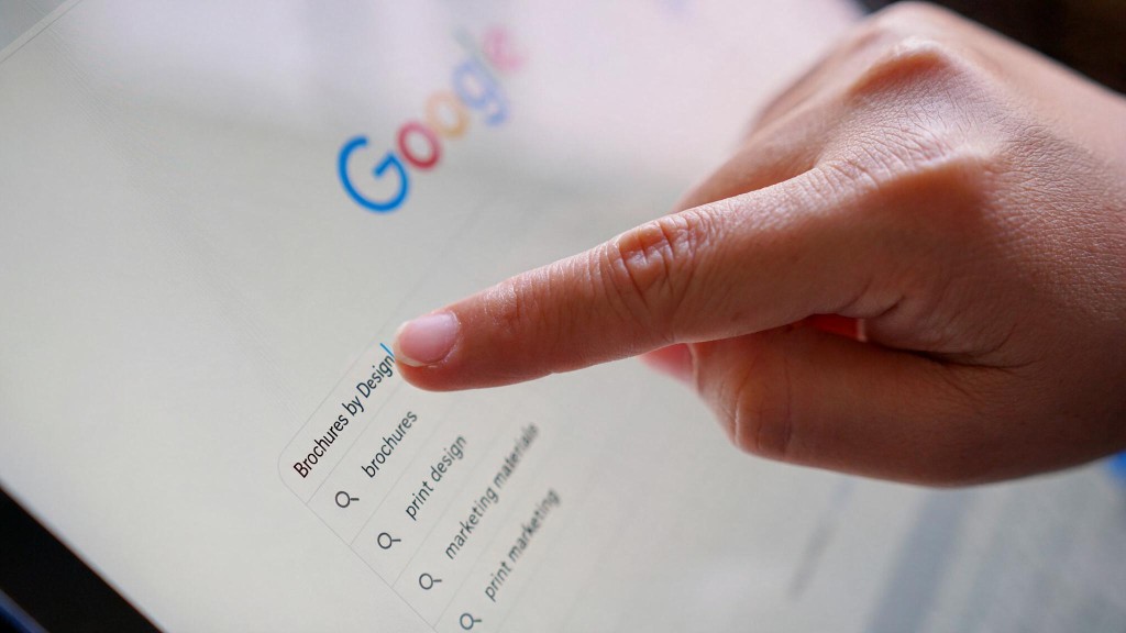 A hand selecting Brochures by Design from Google search suggestions