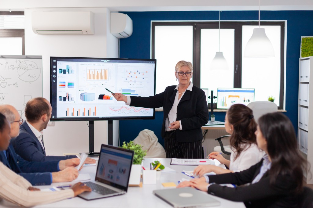 A presenter reviewing charts with a leadership team in a conference room