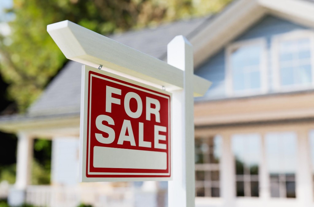 A red For Sale sign in front of a house