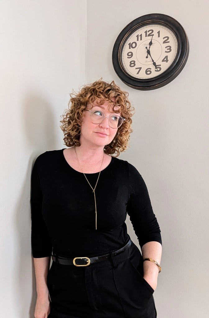 Heidi Beneduci standing beneath a wall clock
